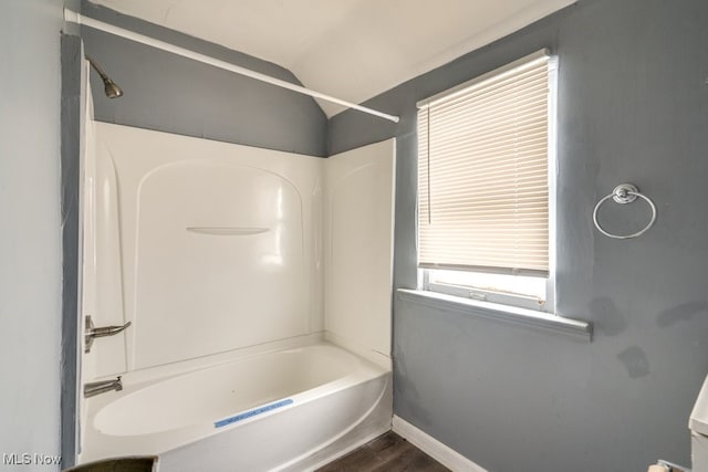 bathroom featuring hardwood / wood-style floors, shower / tub combination, and vaulted ceiling