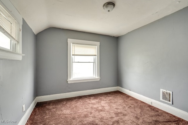 spare room featuring carpet flooring and vaulted ceiling