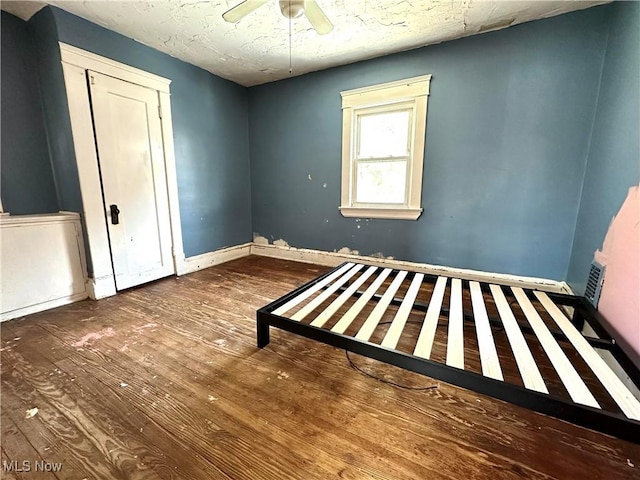 unfurnished bedroom featuring a textured ceiling, dark hardwood / wood-style floors, and ceiling fan