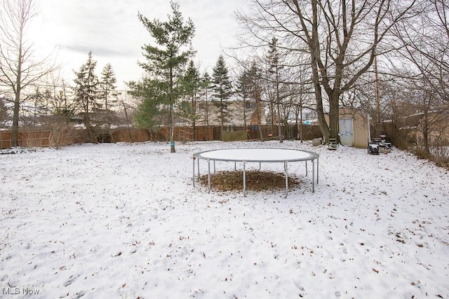 yard covered in snow featuring a trampoline and a storage shed