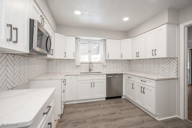 kitchen featuring sink, light stone countertops, dark hardwood / wood-style flooring, white cabinetry, and stainless steel appliances