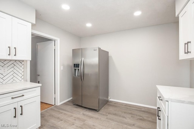 kitchen featuring decorative backsplash, stainless steel refrigerator with ice dispenser, white cabinets, and light hardwood / wood-style flooring