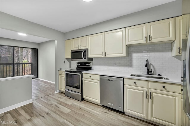 kitchen featuring cream cabinets, sink, stainless steel appliances, and light hardwood / wood-style floors