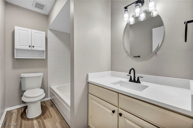 bathroom featuring visible vents, toilet, wood finished floors, baseboards, and vanity