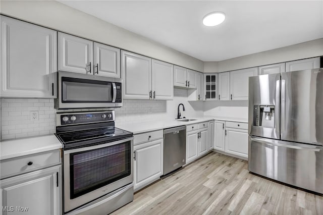 kitchen featuring a sink, appliances with stainless steel finishes, light wood-style flooring, and light countertops