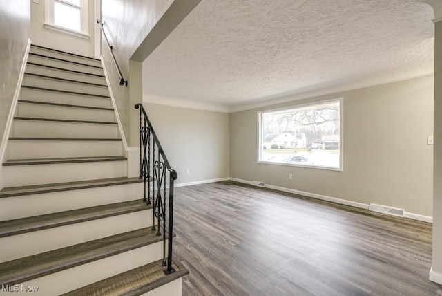 stairway featuring a textured ceiling, hardwood / wood-style flooring, and crown molding