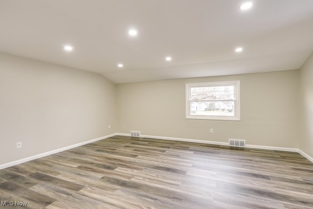 unfurnished room featuring hardwood / wood-style flooring and lofted ceiling