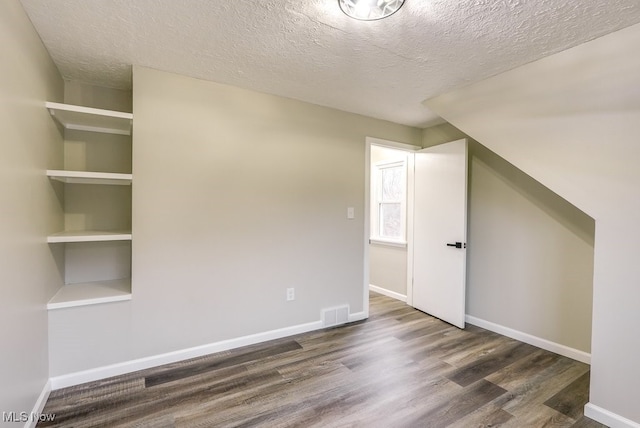 bonus room featuring dark hardwood / wood-style flooring and a textured ceiling