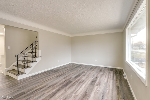 spare room with crown molding, a textured ceiling, and hardwood / wood-style flooring