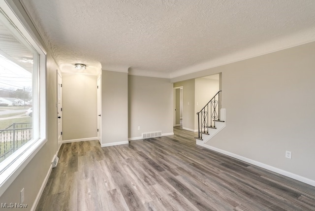 spare room featuring a textured ceiling and dark hardwood / wood-style floors