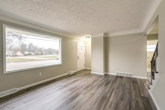 unfurnished room featuring a wealth of natural light, dark wood-type flooring, and a textured ceiling