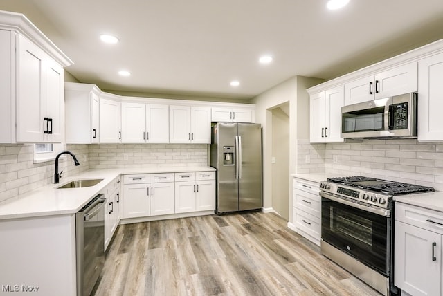 kitchen featuring white cabinets, sink, light hardwood / wood-style flooring, decorative backsplash, and stainless steel appliances