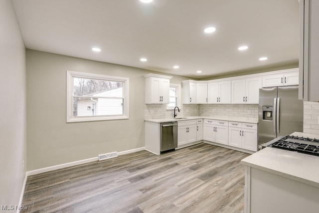 kitchen featuring white cabinets, decorative backsplash, sink, and appliances with stainless steel finishes