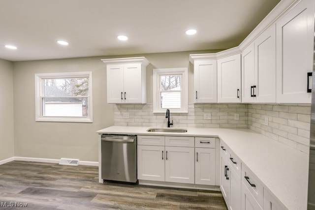 kitchen with white cabinetry, sink, stainless steel dishwasher, wood-type flooring, and decorative backsplash