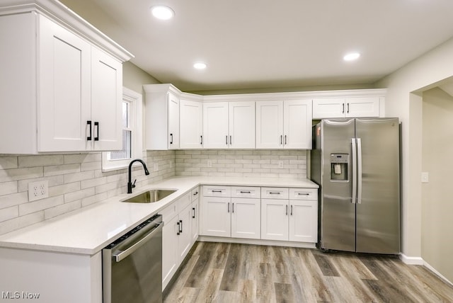 kitchen featuring appliances with stainless steel finishes, backsplash, white cabinetry, and sink