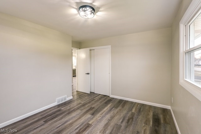 unfurnished bedroom featuring a closet and dark wood-type flooring