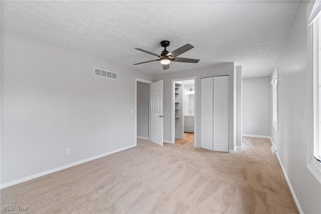 unfurnished bedroom featuring ceiling fan, light carpet, and a textured ceiling