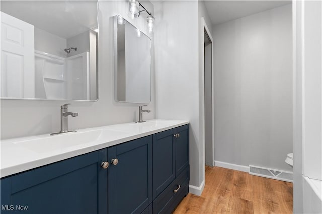 bathroom featuring a shower, hardwood / wood-style floors, vanity, and toilet