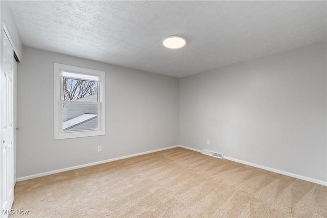 carpeted spare room with a textured ceiling