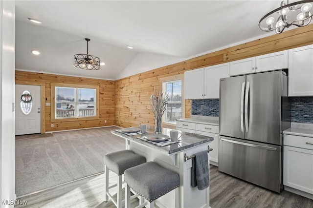 kitchen with white cabinetry, vaulted ceiling, hanging light fixtures, and stainless steel fridge