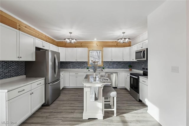 kitchen featuring white cabinetry, hanging light fixtures, stainless steel appliances, and a center island