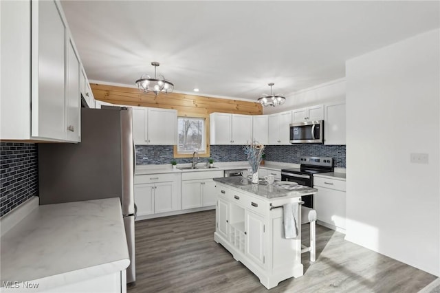 kitchen with stainless steel appliances, hanging light fixtures, a center island, and white cabinets