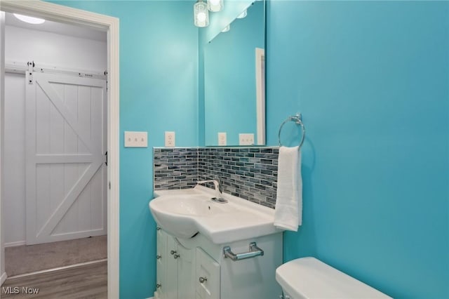 bathroom with vanity, toilet, hardwood / wood-style floors, and decorative backsplash