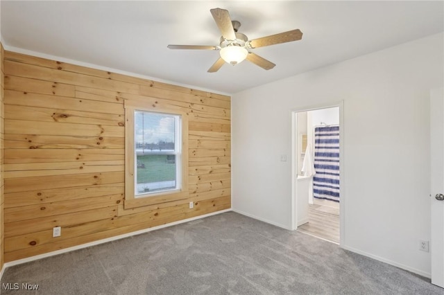 carpeted spare room with wooden walls and ceiling fan