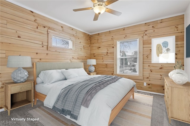 carpeted bedroom featuring ceiling fan and wood walls