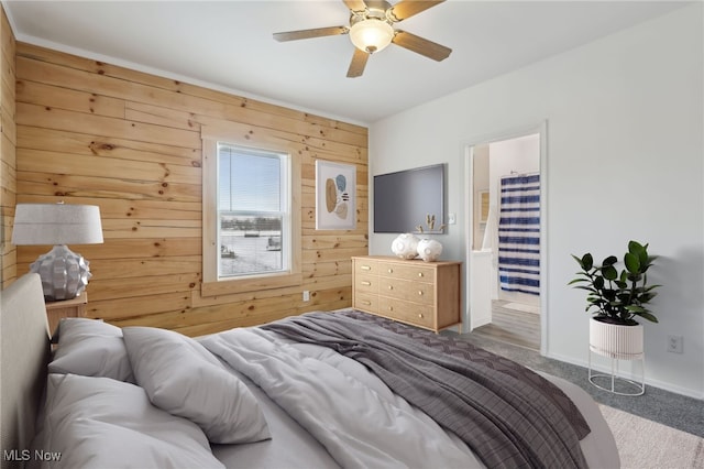 bedroom with a walk in closet, carpet, ceiling fan, and wood walls