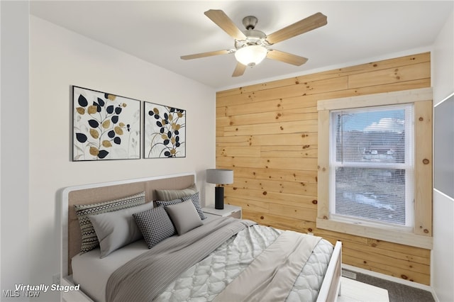 bedroom with ceiling fan, carpet, and wood walls