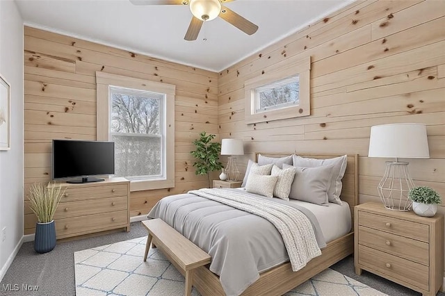 bedroom featuring wooden walls, light colored carpet, and ceiling fan