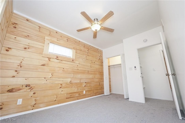 unfurnished bedroom with ceiling fan, light carpet, and wooden walls