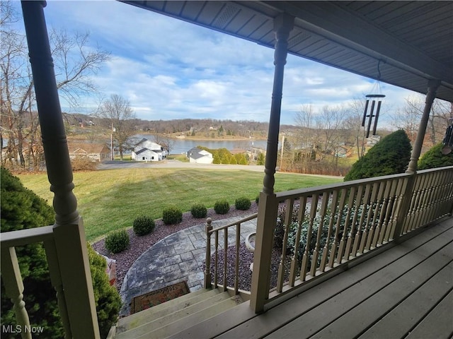 wooden terrace with covered porch, a water view, and a lawn