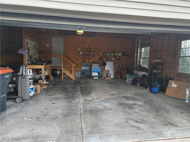 garage featuring a workshop area, a garage door opener, and wooden walls