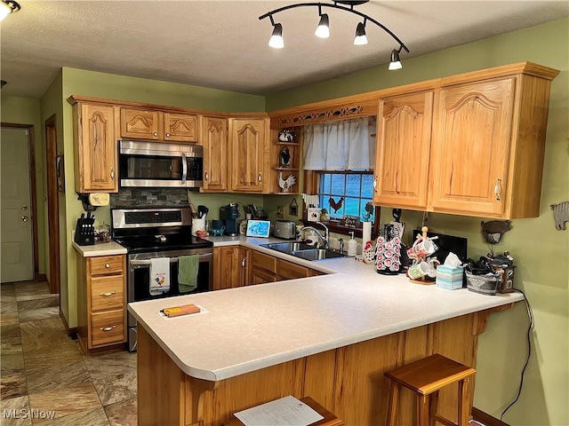 kitchen featuring kitchen peninsula, a kitchen breakfast bar, decorative backsplash, stainless steel appliances, and sink