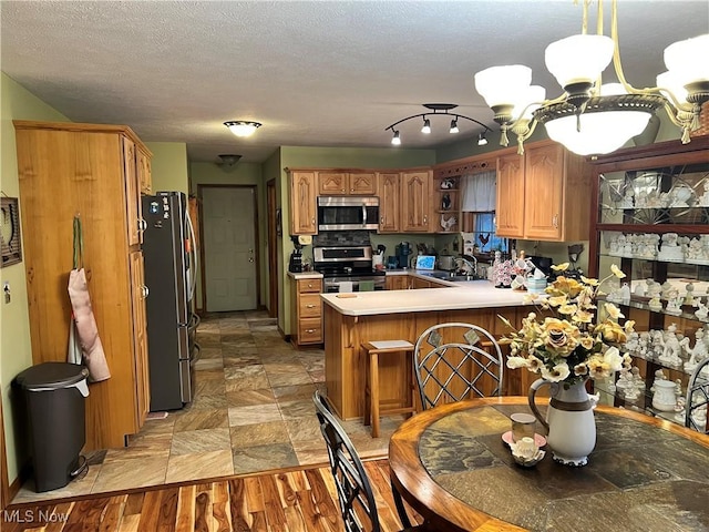 kitchen featuring an inviting chandelier, sink, hanging light fixtures, appliances with stainless steel finishes, and kitchen peninsula