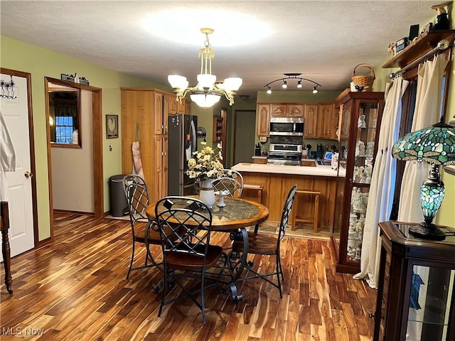 dining area with a textured ceiling, dark hardwood / wood-style floors, and a notable chandelier