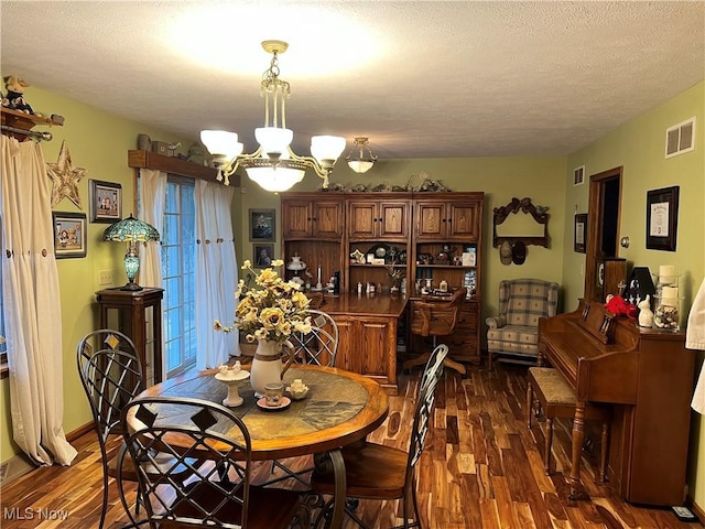 dining space featuring a textured ceiling, dark hardwood / wood-style floors, and an inviting chandelier