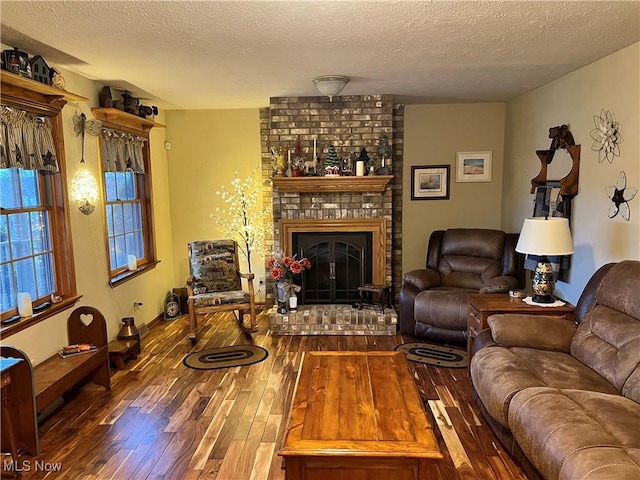 living room with hardwood / wood-style floors, a textured ceiling, and a brick fireplace