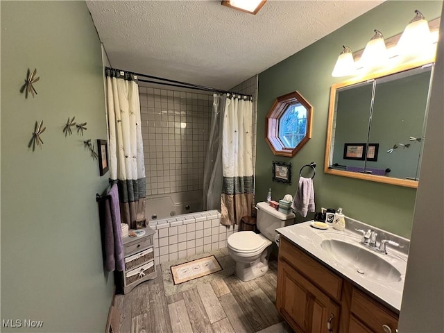 full bathroom featuring hardwood / wood-style floors, a textured ceiling, toilet, shower / bath combo with shower curtain, and vanity