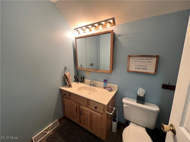 bathroom featuring tile patterned floors, vanity, toilet, and a textured ceiling