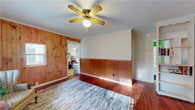 sitting room with ceiling fan, dark hardwood / wood-style flooring, wood walls, and ornamental molding