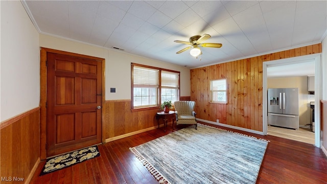 sitting room with ceiling fan, ornamental molding, and dark wood-type flooring