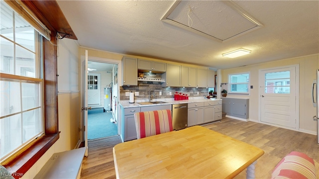kitchen with decorative backsplash, a textured ceiling, sink, dishwasher, and light hardwood / wood-style floors