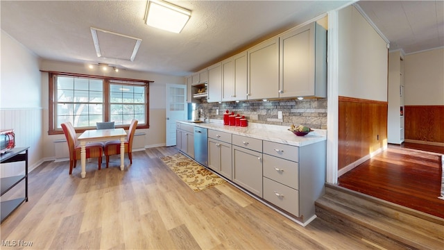 kitchen featuring sink, stainless steel dishwasher, a textured ceiling, gray cabinets, and light wood-type flooring