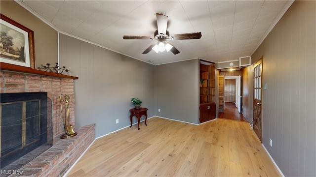 living room featuring a fireplace, light hardwood / wood-style floors, ceiling fan, and crown molding