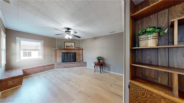 unfurnished living room with ceiling fan, light hardwood / wood-style floors, and a brick fireplace