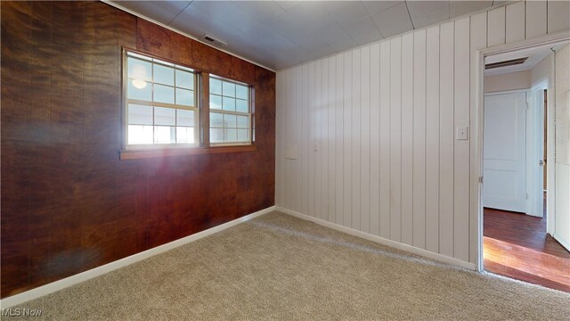 spare room featuring carpet flooring and wood walls