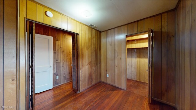 interior space with dark hardwood / wood-style flooring and wood walls